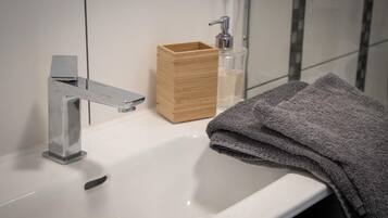 Un baño con un lavamanos blanco, una caja de madera y una botella de jabón.