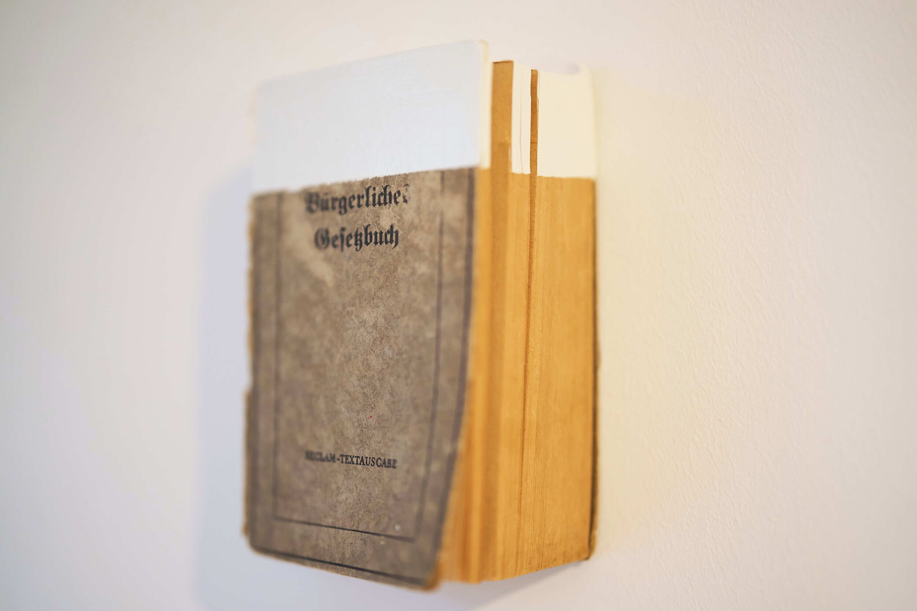 A book titled "Burgerliches Gebuch" with a worn cover, placed against a plain wall.