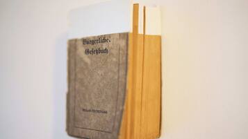 A book titled "Burgerliches Gebuch" with a worn cover, placed against a plain wall.