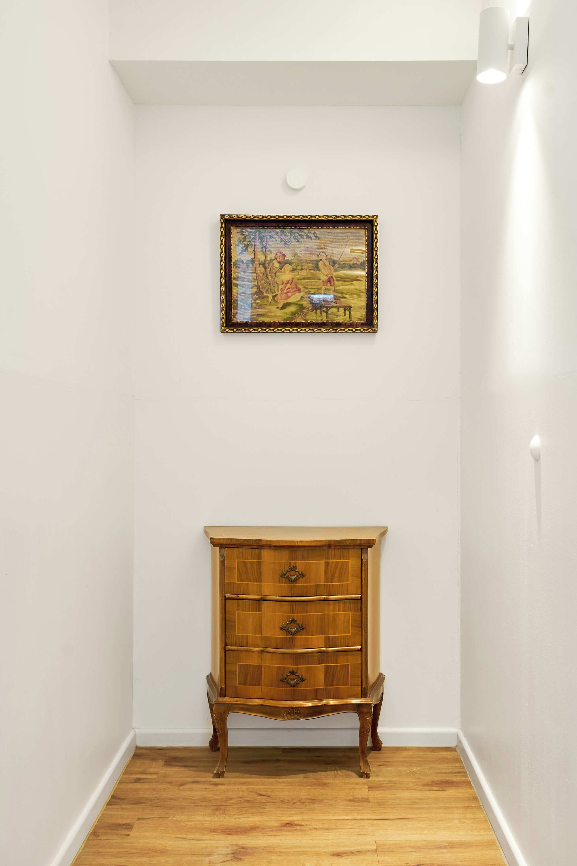 Una habitación de esquina con un armario de madera y un cuadro enmarcado en la pared.