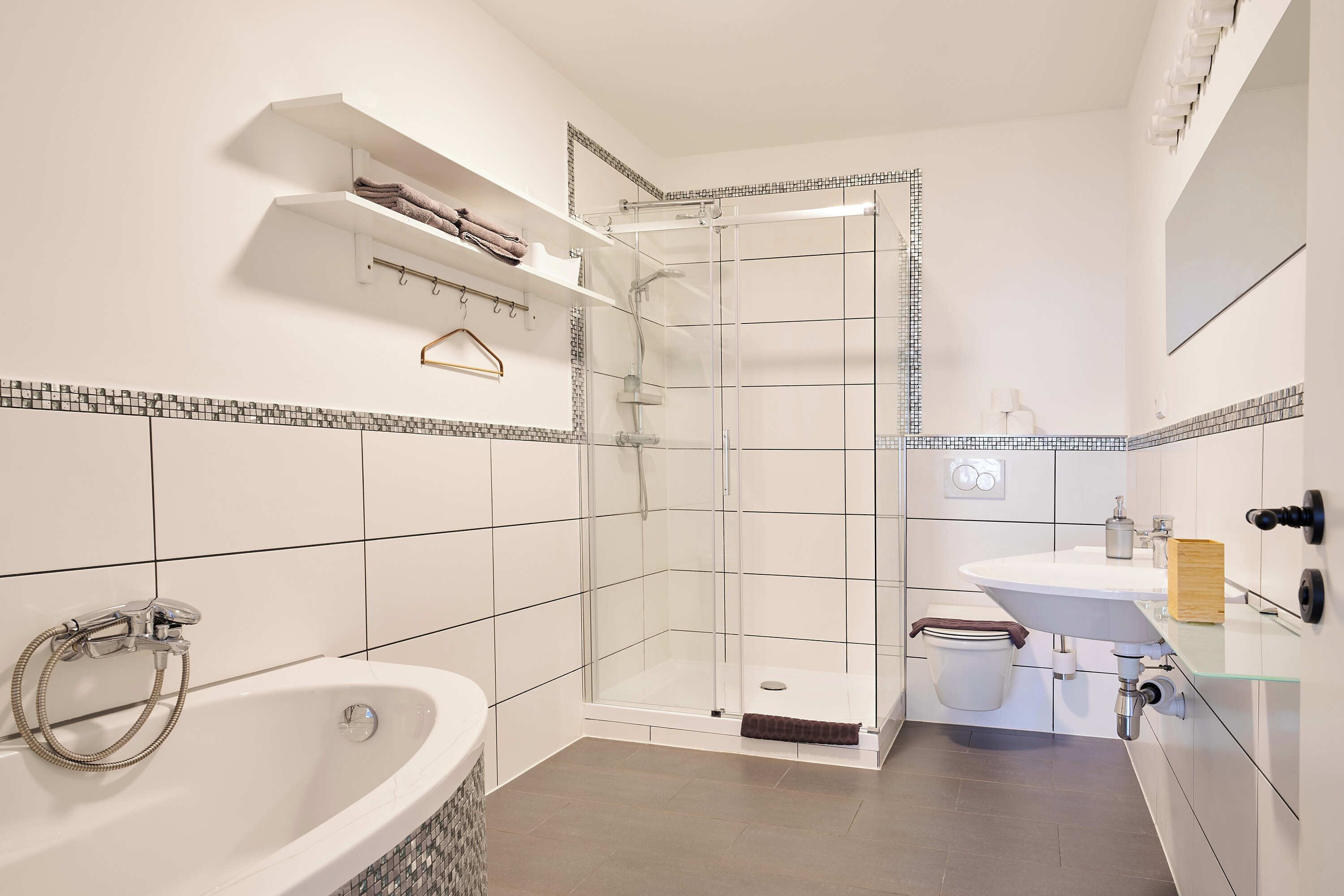 Ein modernes Badezimmer mit einer Duschkabine, einer freistehenden Badewanne und einem Waschtisch.