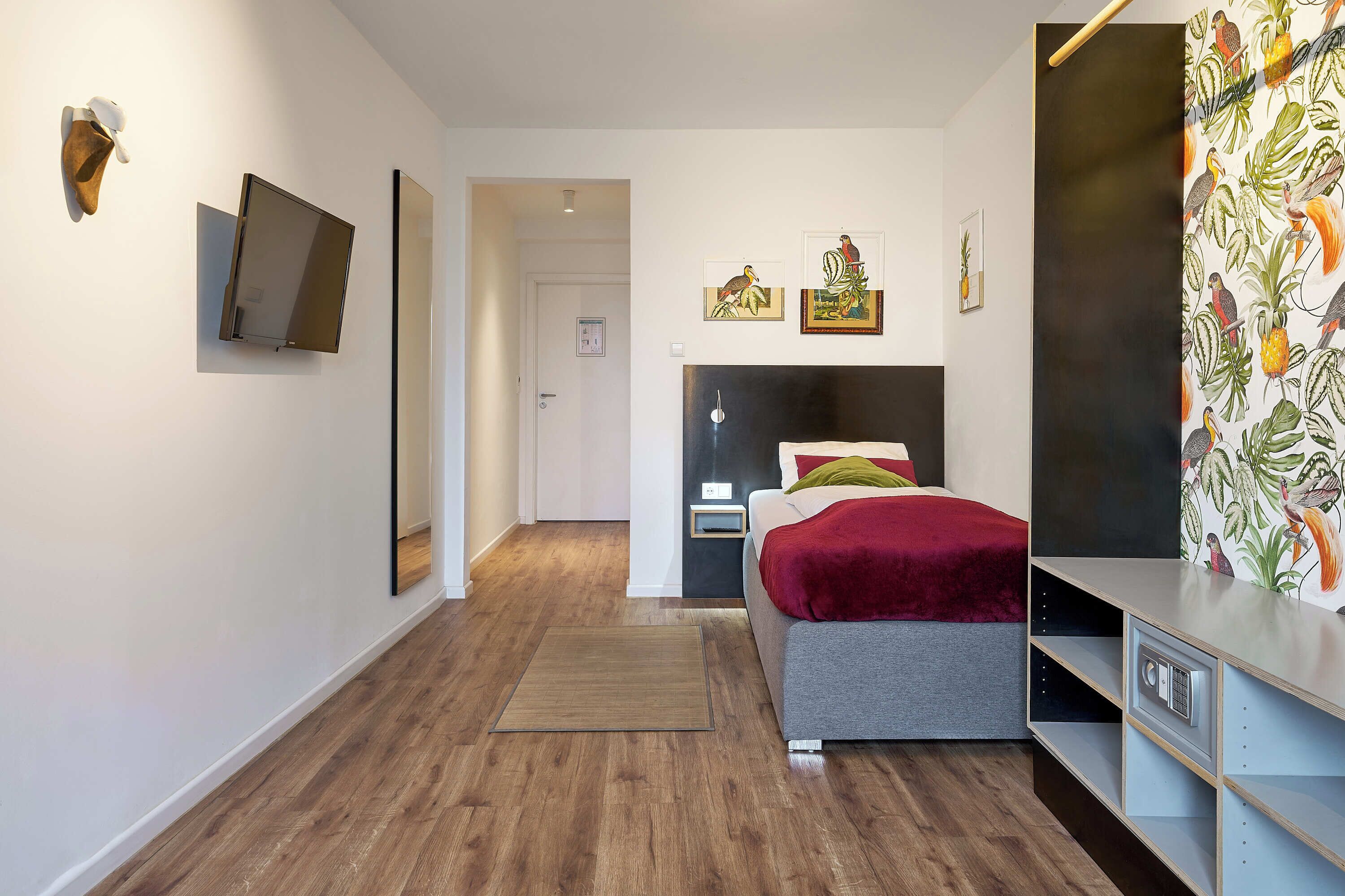 Ein modernes Schlafzimmer mit Bett, Nachttischen, einem Fernseher und Kunstwerken an den Wänden.