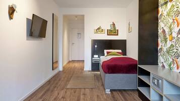 Ein modernes Schlafzimmer mit Bett, Nachttischen, einem Fernseher und Kunstwerken an den Wänden.