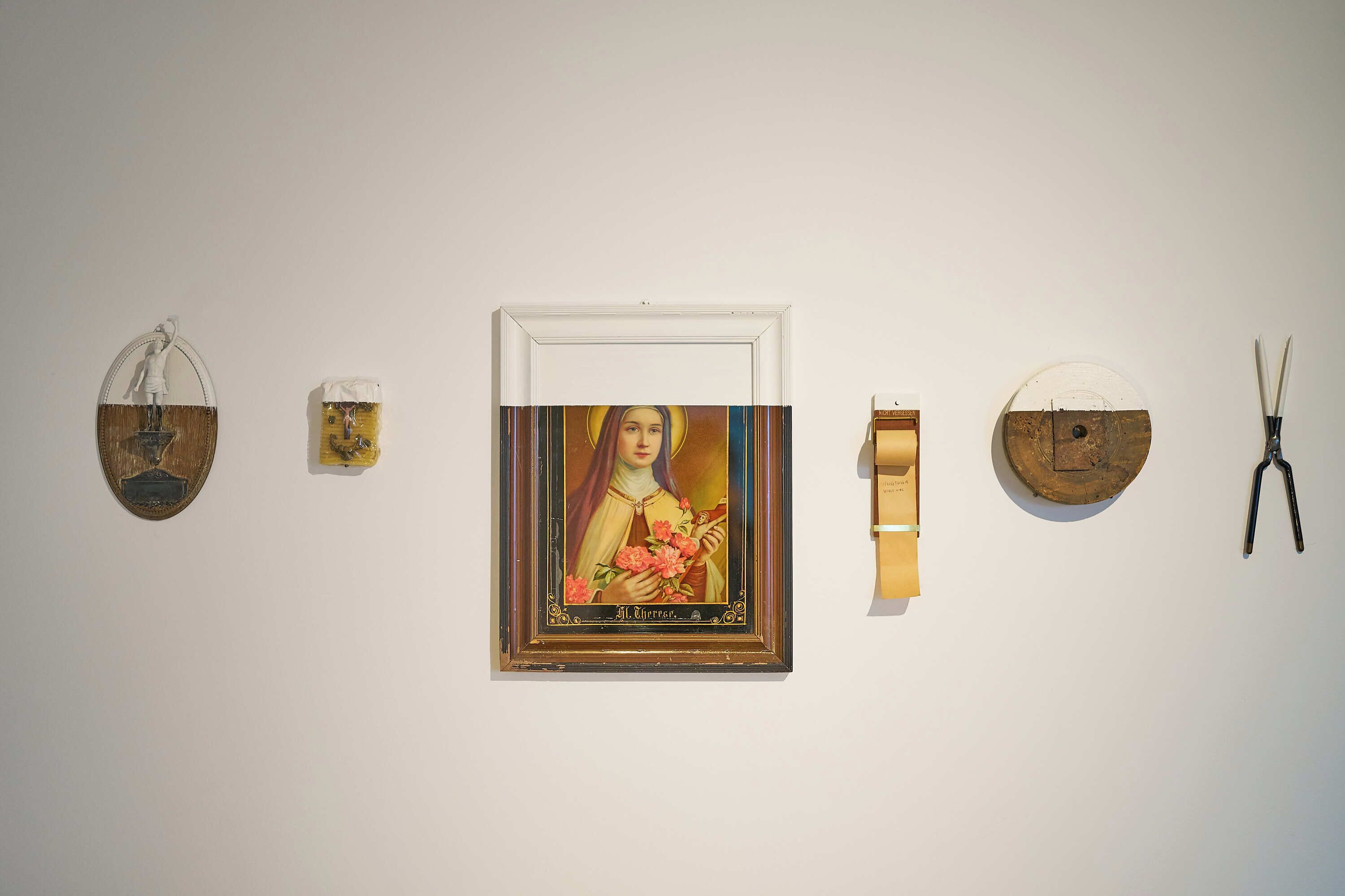 Una parete con diversi oggetti, tra cui un quadro incorniciato, una piccola scultura e un paio di forbici.