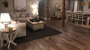 A spacious living room with a sofa, coffee table, and a dining area with a table and chairs. - Greer’s Ferry Lake & Little Red River Cabin (Heber Springs)