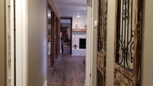 A hallway with wooden flooring, white walls, and a fireplace. - Greer’s Ferry Lake & Little Red River Cabin (Heber Springs)