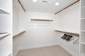 Un dressing avec des murs blancs, un banc en bois et un portant pour suspendre les vêtements.