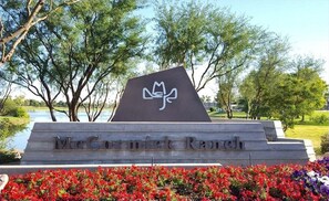 A sign with the text "McCormick Ranch" and a logo, surrounded by trees and flowers.
