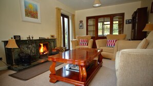 A cozy living room with a fireplace, comfortable seating, and a large wooden coffee table. - Riverfield Bed and Breakfast (Gorey)