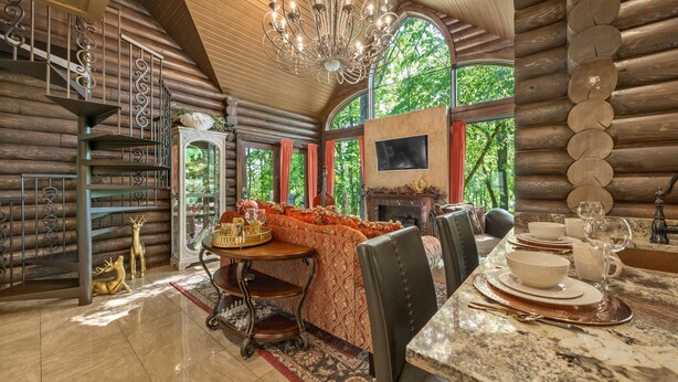 A log cabin interior with a dining area, a fireplace, and a chandelier. - Romance-Grande Old World-Lux Hot Tub-Kayaks-Private Spa w/ Massage Chair & Sauna (Logan)