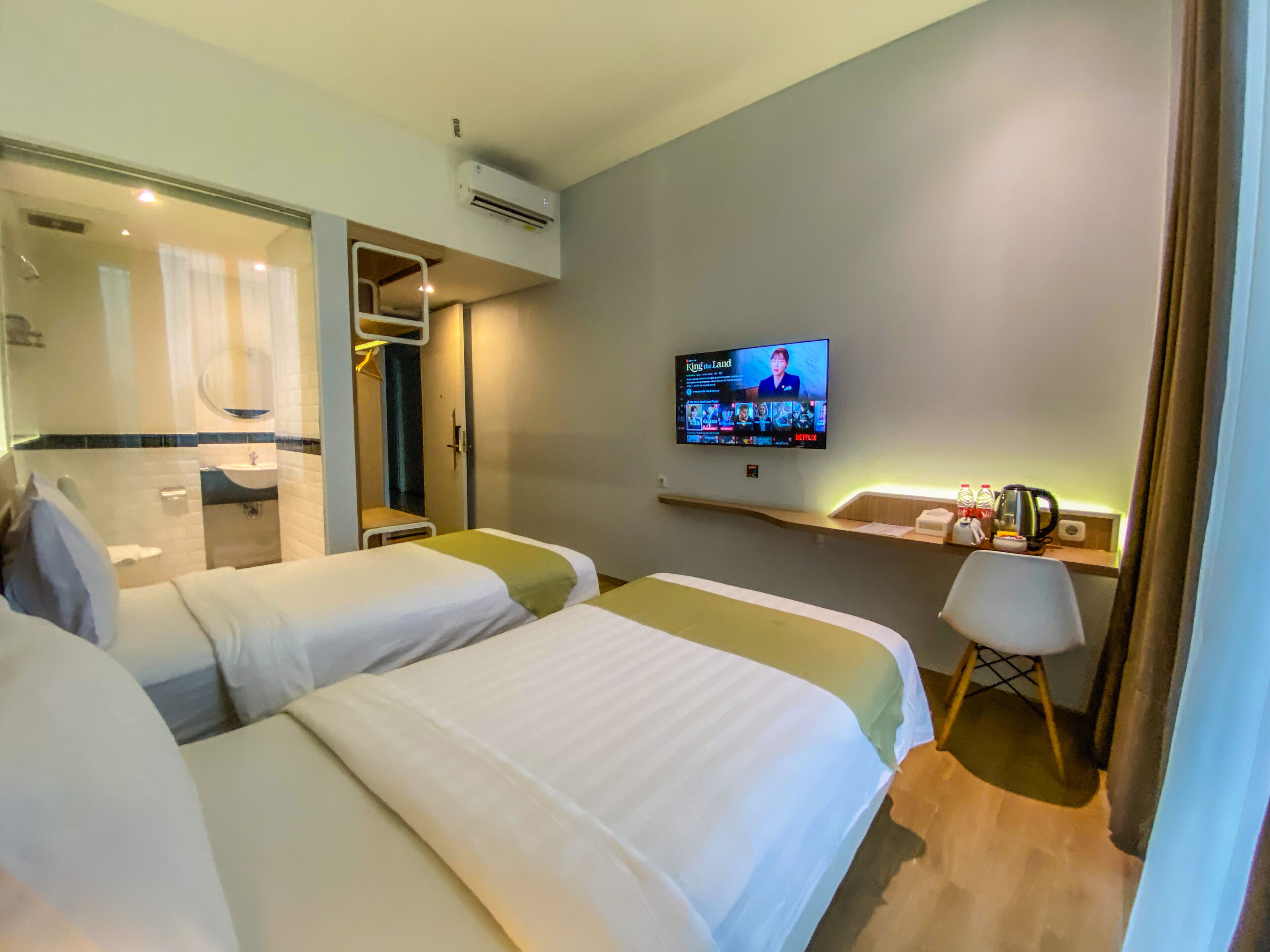 A hotel room with two beds, a TV, a desk, and a chair.