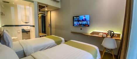 A hotel room with two beds, a TV, a desk, and a chair.