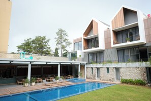 Un edificio moderno con piscina, asientos al aire libre y una pared de piedra.