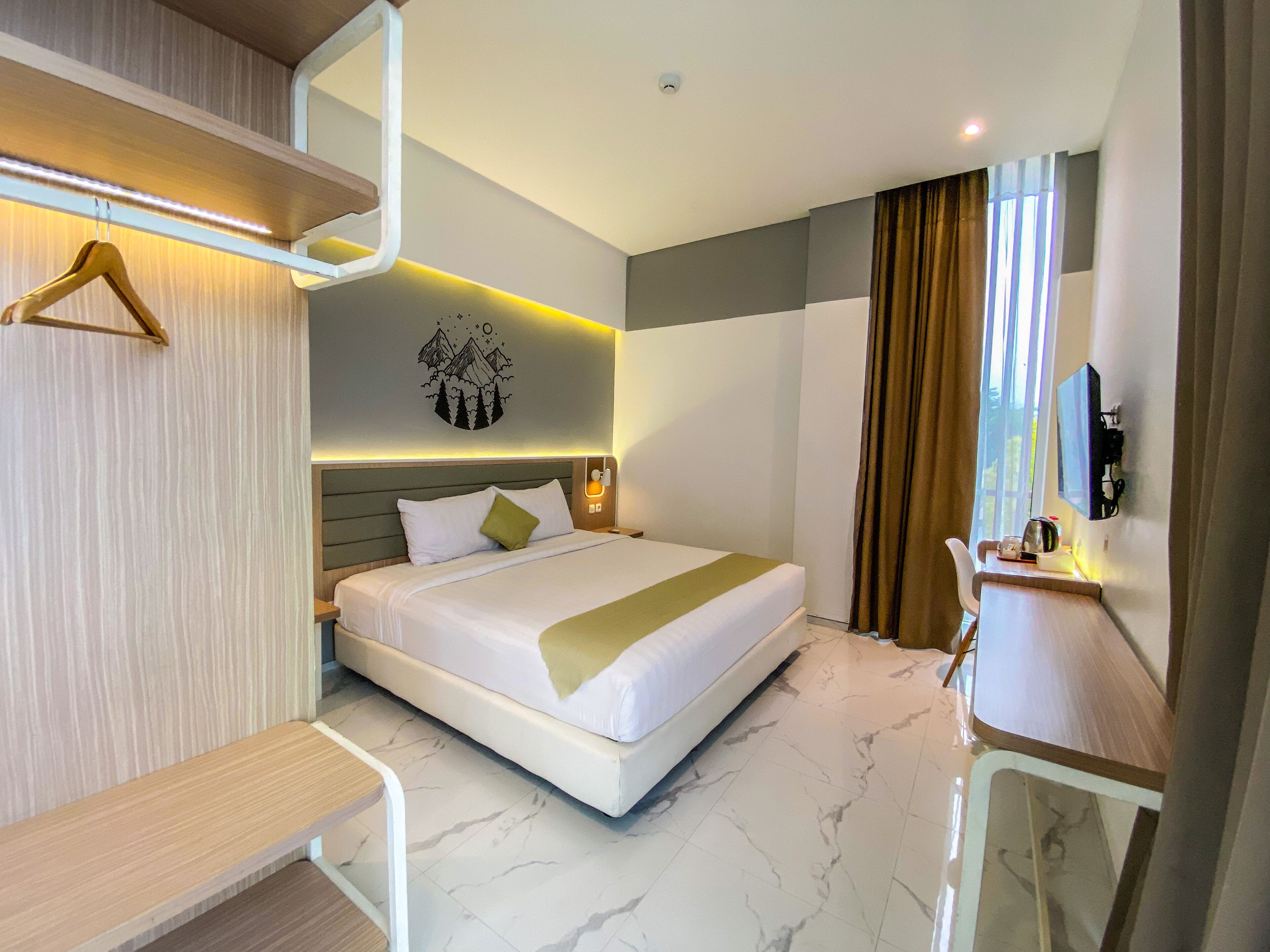 A modern hotel room with a large bed, a desk, and a TV.