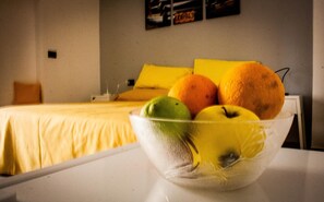 A room with a bed, a white table, and a bowl of fruit on the table. - Interno 10 (Syracuse)