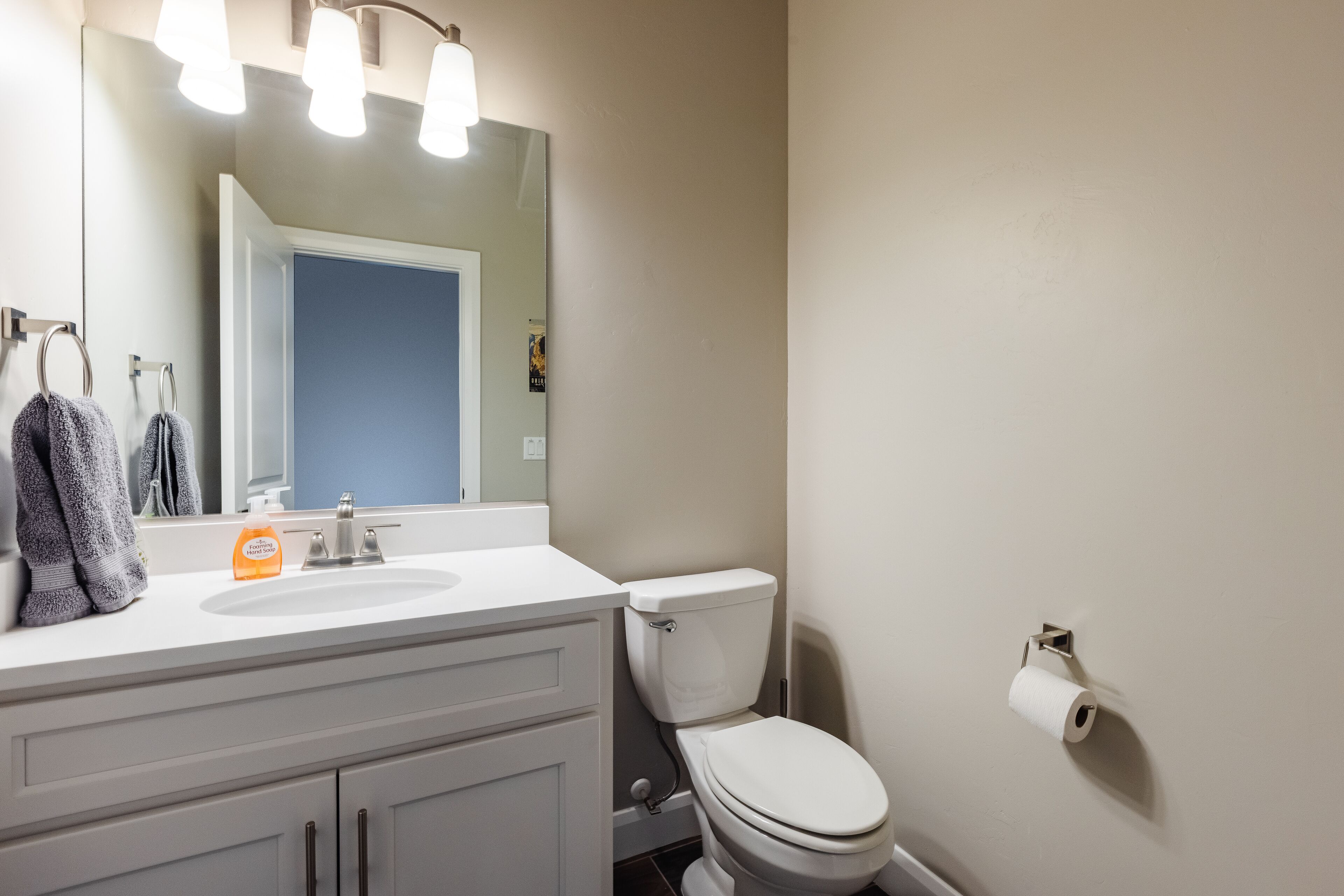 A bathroom with a white sink, a mirror, a toilet, and a towel rack.