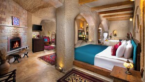 A cozy room with a fireplace, a bed with colorful pillows, and a wooden ceiling.