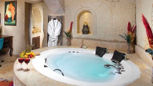A spa room with a large bathtub, a towel rack, and a statue.