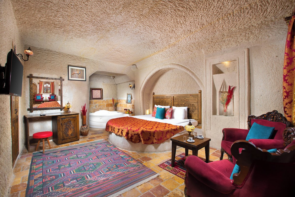 A traditional room with a bed, a desk, a chair, a sofa, and a rug.
