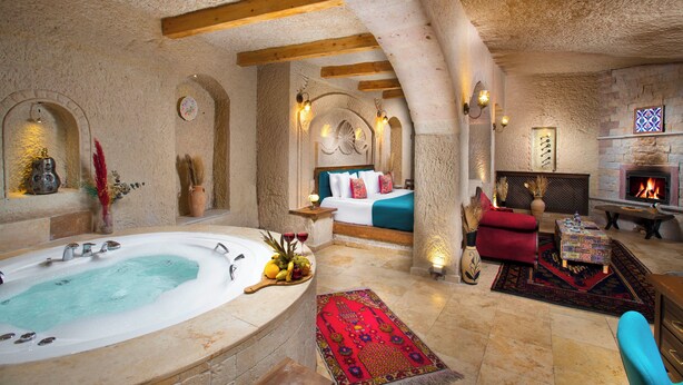 A luxurious room with a large bathtub, a cozy seating area, a fireplace, and a bed with a view of the room.