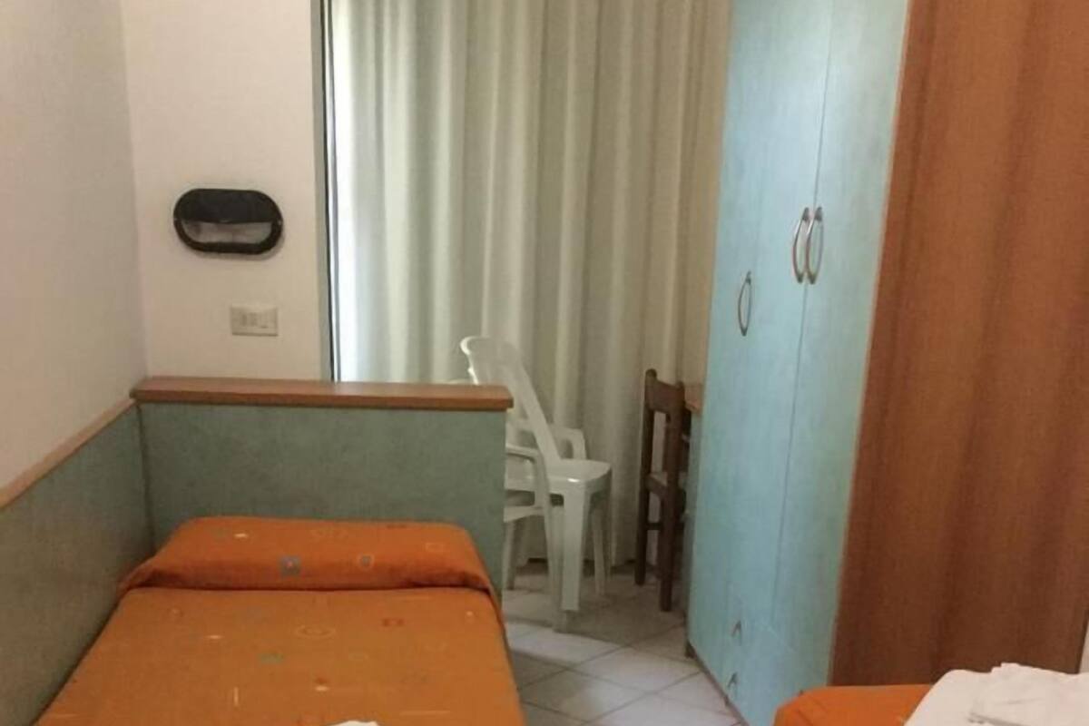A room with two single beds, a small table, a chair, and a wardrobe.