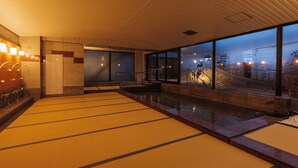 A spacious indoor area with a large window, a reception desk, and a seating area with a view of a bridge. - Shionomaru (Imabari)
