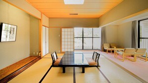 A traditional tatami mat room with a long table, chairs, and a large window. - Shionomaru (Imabari)