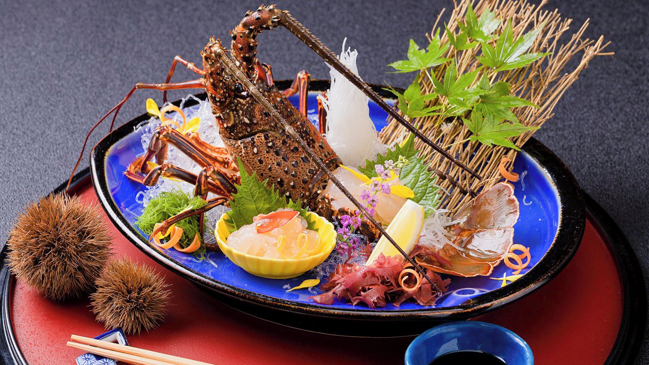 A seafood platter with various items including a lobster, shrimp, and other seafood, accompanied by vegetables and garnishes.