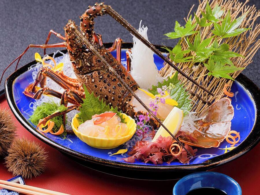 A seafood platter with various items including a lobster, shrimp, and other seafood, accompanied by vegetables and garnishes.