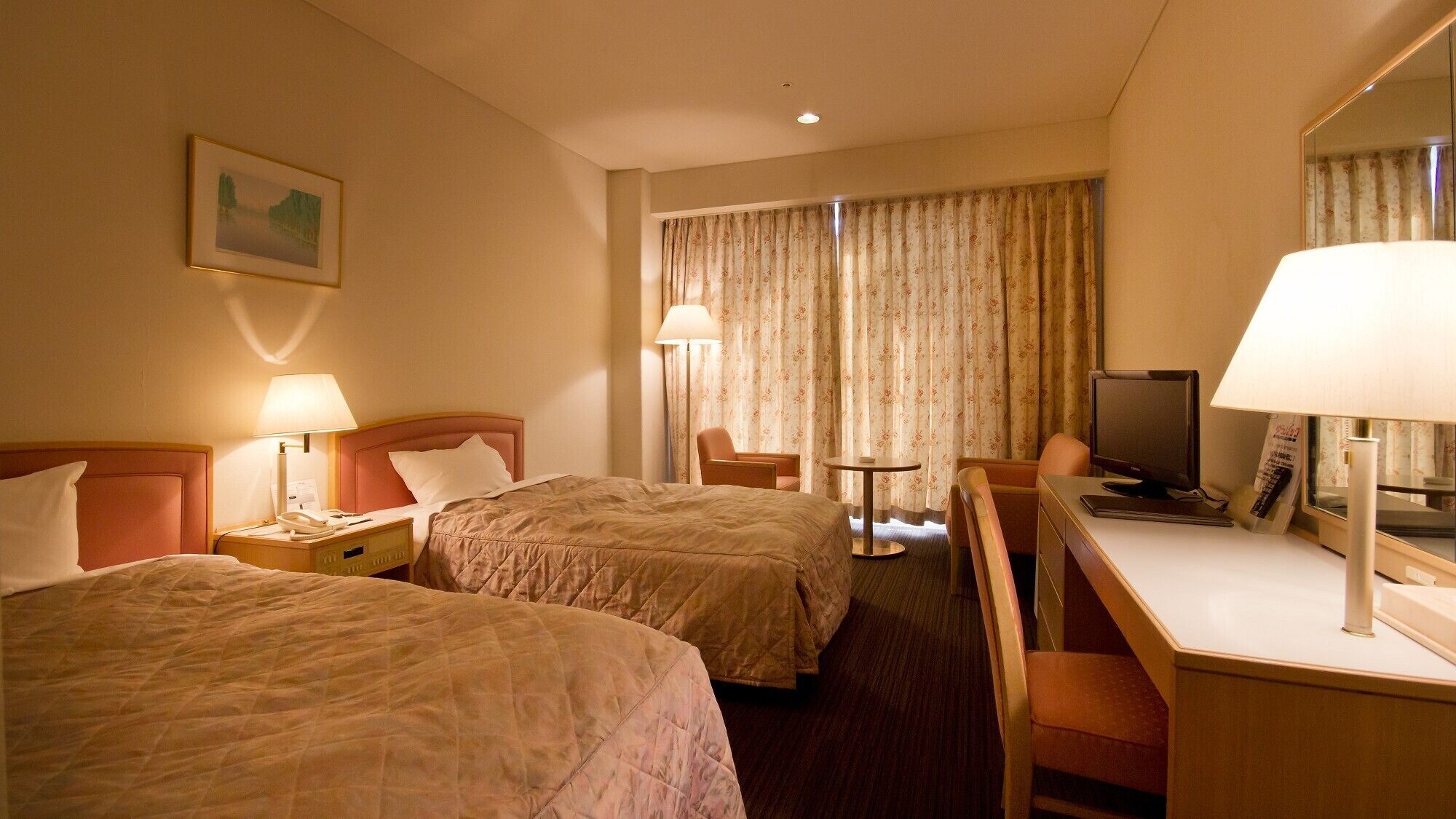 Een hotelkamer met twee bedden, een bureau, een stoel, een televisietoestel en een lamp.