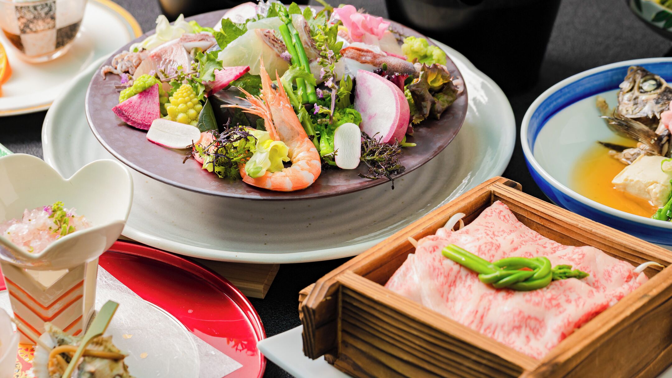A variety of dishes including seafood, vegetables, and tofu, presented on a ceramic plate.