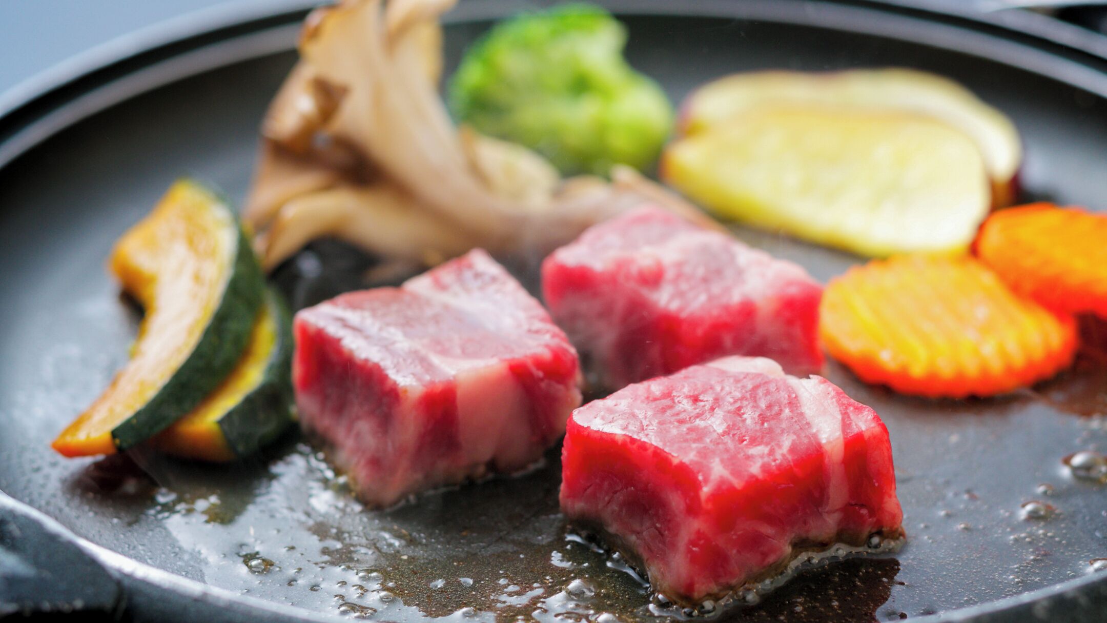A pan with raw meat, vegetables, and a sauce.