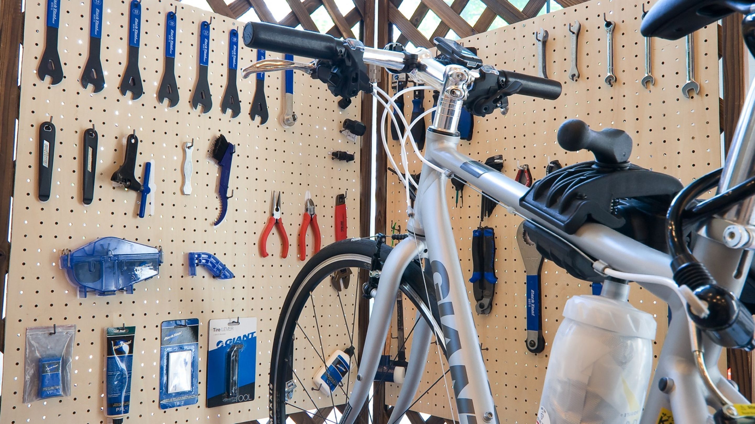 A bicycle in a workshop with tools and equipment on pegboards.