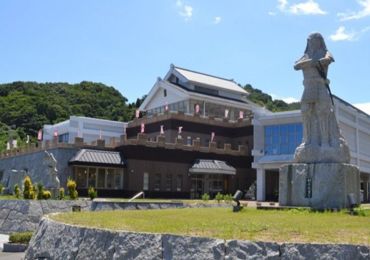 Een traditioneel Japans gebouw met een groot standbeeld ervoor.