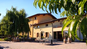 A courtyard with a table tennis table, potted plants, and a building with a balcony. - Agriturismo La Molinalda (Castelnuovo del Garda)