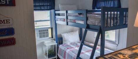 Habitación con literas, un escritorio pequeño y una lámpara.