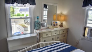 A bedroom with a bed, dresser, mirror, and windows. - Three bedroom duplex less than 500 ft to the shared/private beach (West Dennis)