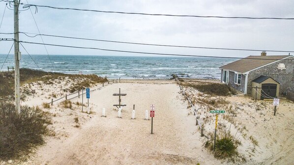 Una playa arenosa con una estructura de madera y un poste con indicaciones.