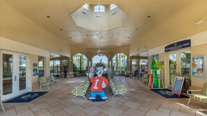 A covered outdoor area with a central seating area, a ceiling fan, and a sign for 'The Marketplace & Grill'.