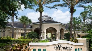 A Windsor Hills Clubhouse with a Mediterranean-style building, surrounded by lush greenery and palm trees.