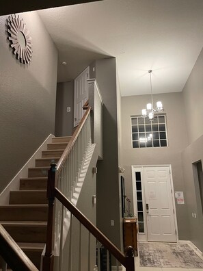 A staircase with wooden railings leading to a landing with a chandelier and a door.