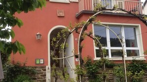 Un edificio rosso con base in pietra, un balcone e un giardino con sedie e tavoli.