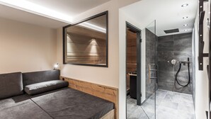 Un baño moderno con cabina de ducha de vidrio, un banco de madera y un espejo grande.