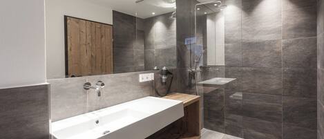 A modern bathroom with a large white sink, a wooden vanity, and a glass-enclosed shower area.