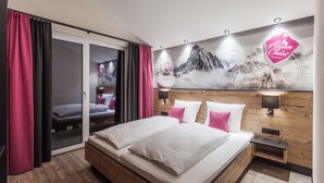 Una habitación de hotel moderna con una cama grande, cabecera de madera y un mural con vistas a la ciudad.