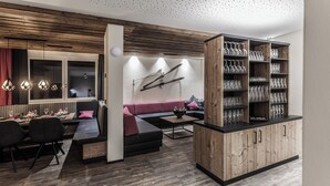 Una sala de estar moderna con una pared de acento de madera, un sofá negro, un comedor con una mesa dispuesta para cuatro personas y una vinoteca.