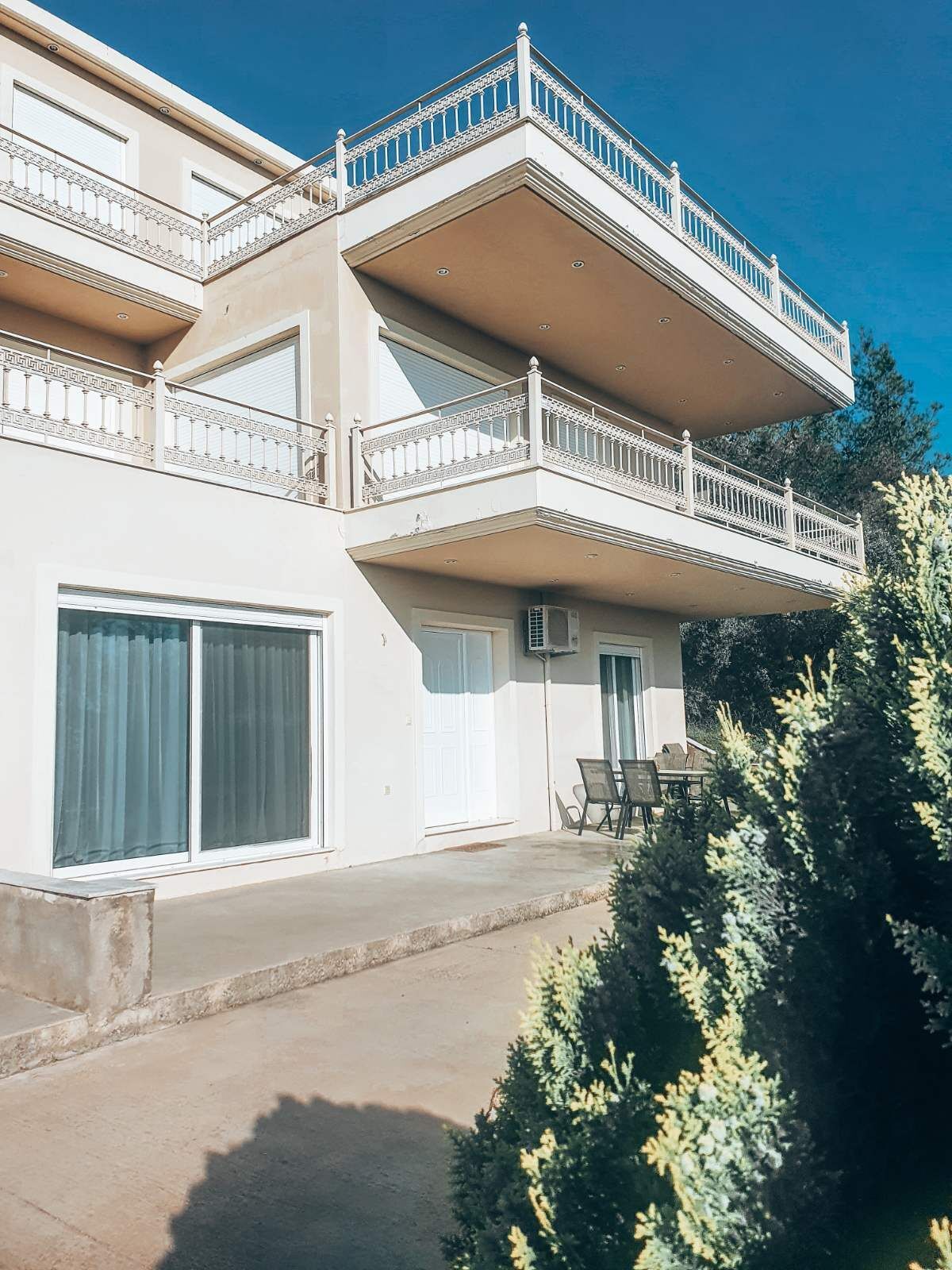 A two-story building with balconies, large windows, and a patio area.