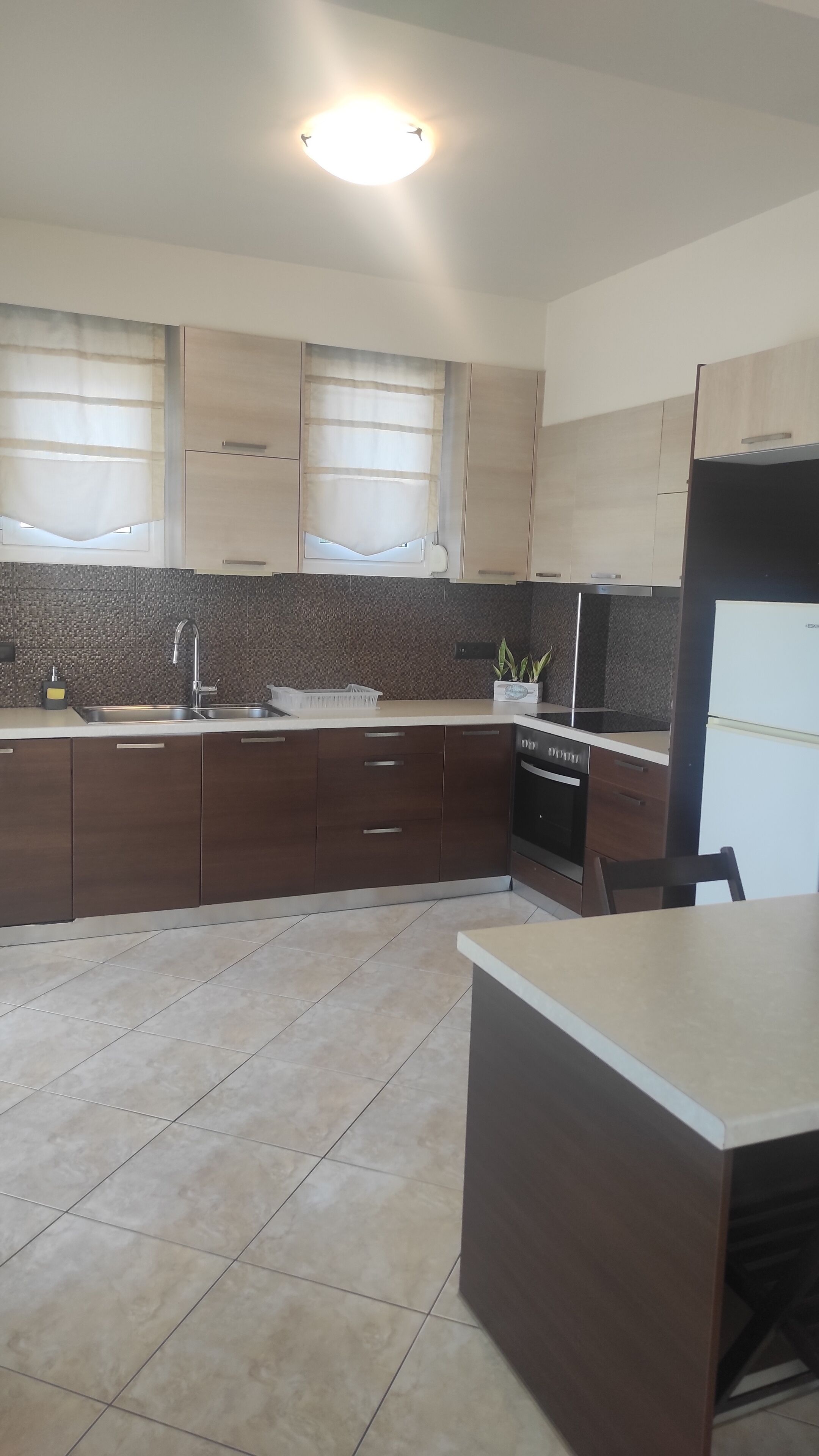 A modern kitchen with dark wooden cabinets, a white countertop, and a built-in oven.