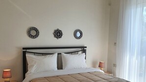 A neatly made bed with a brown quilt, two bedside lamps, and three wall decorations. - Agriomata Vergas Apartments (Kalamata)