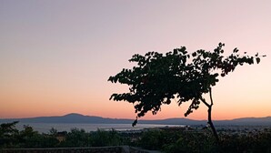 A round glass table with a potted plant and a candle holder, set against a sunset view. - Agriomata Vergas Apartments (Kalamata)